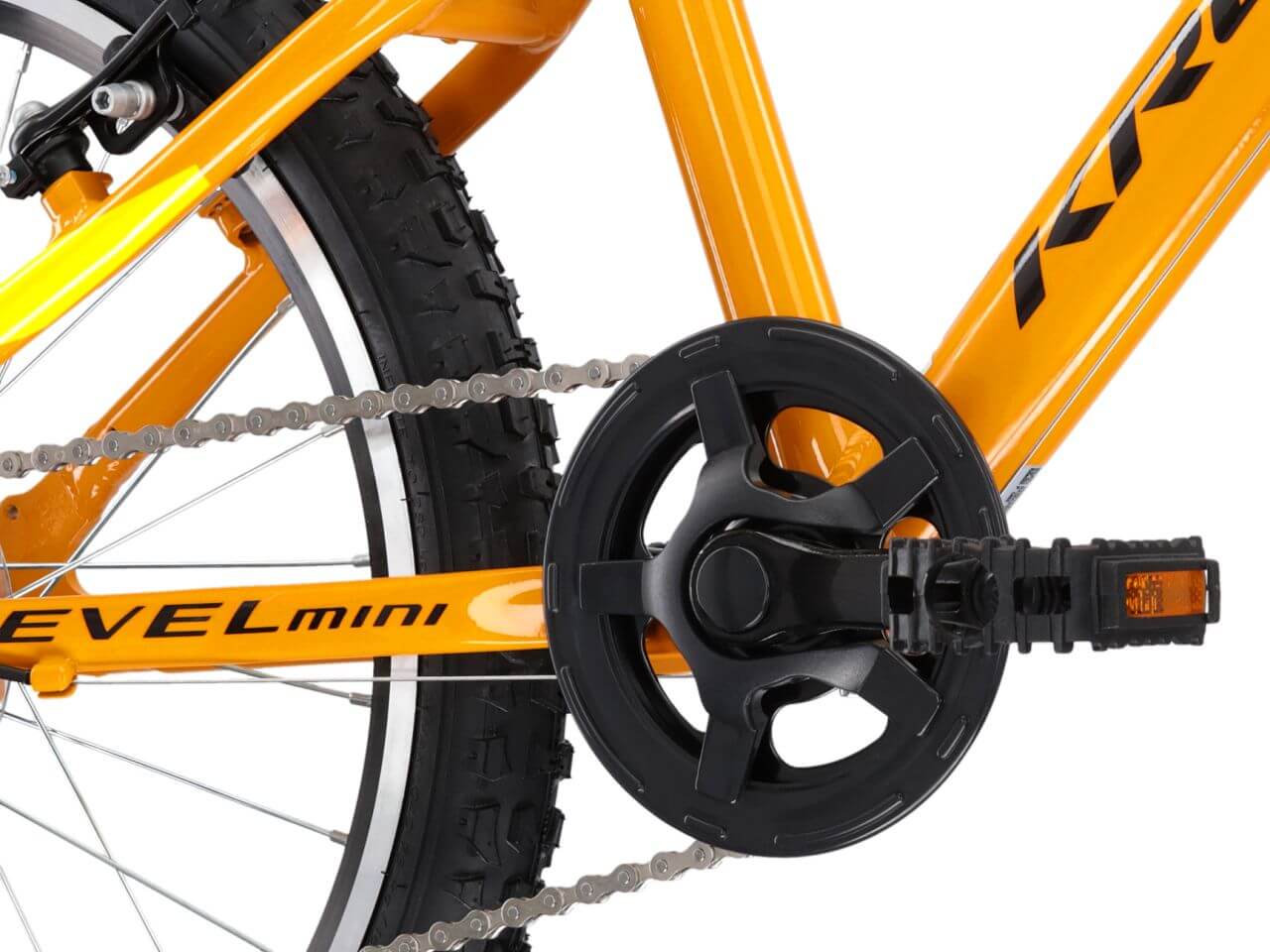 Detail van de KR LEVEL MINI 2.0 fiets, met een focus op de ketting en pedalen in feloranje kleuren.